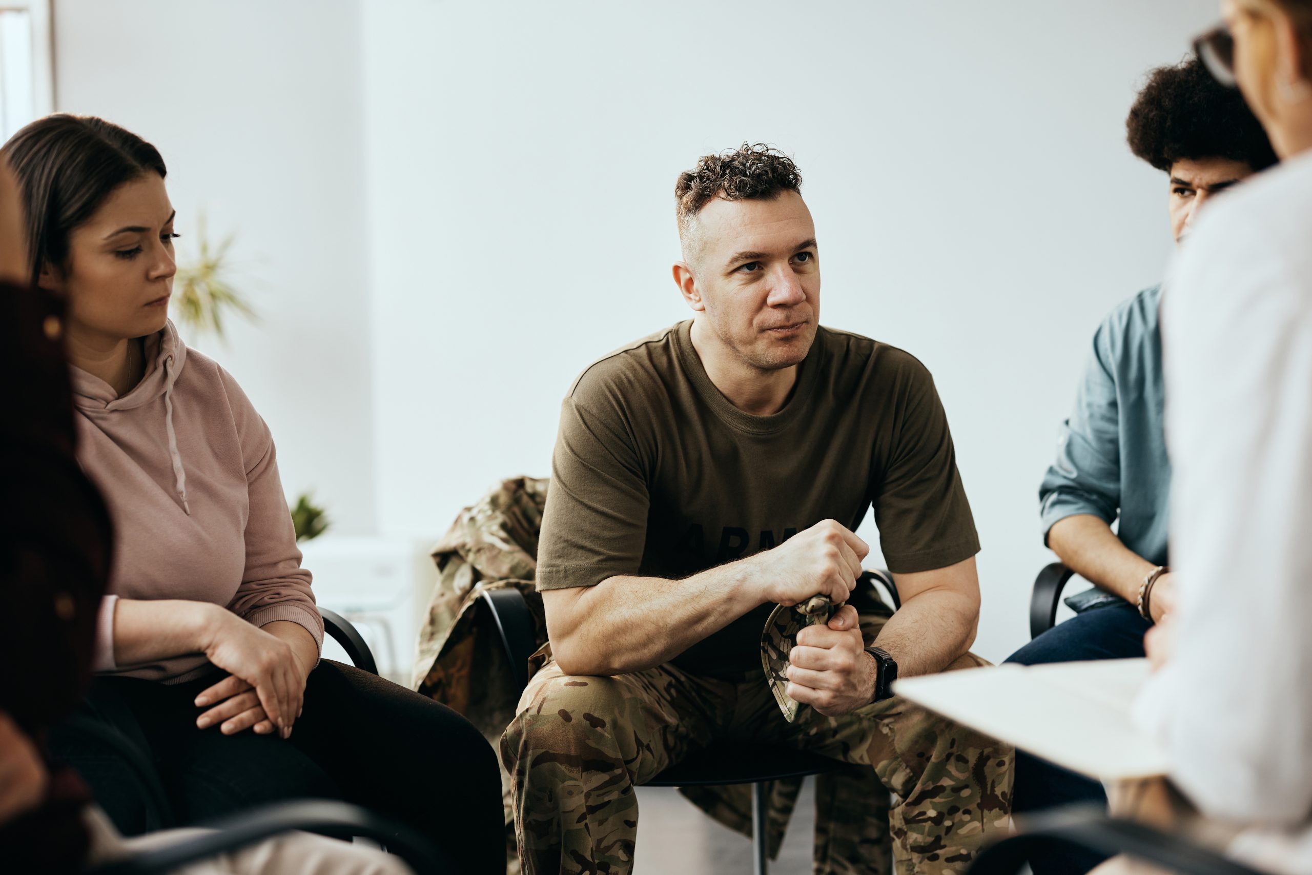 Military officer listening to therapist while having group therapy meeting at community center.
